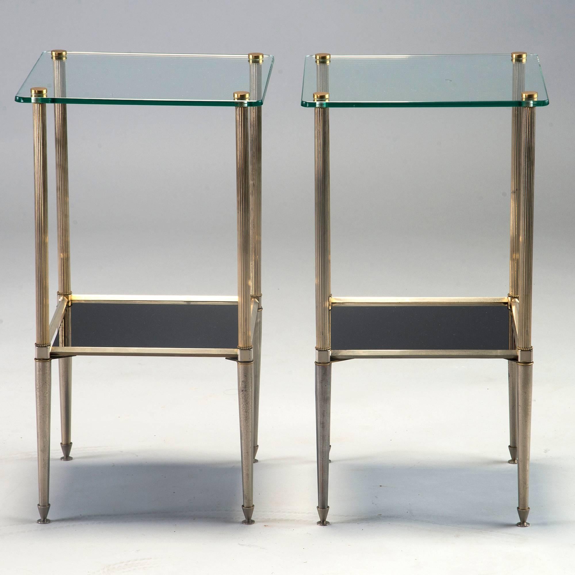 Pair of two-tier side tables, circa 1970s. Reeded brass legs support tops of clear glass and silvered metal supports lower tier of black glass. Unknown maker, found in France. Sold and priced as a pair.
