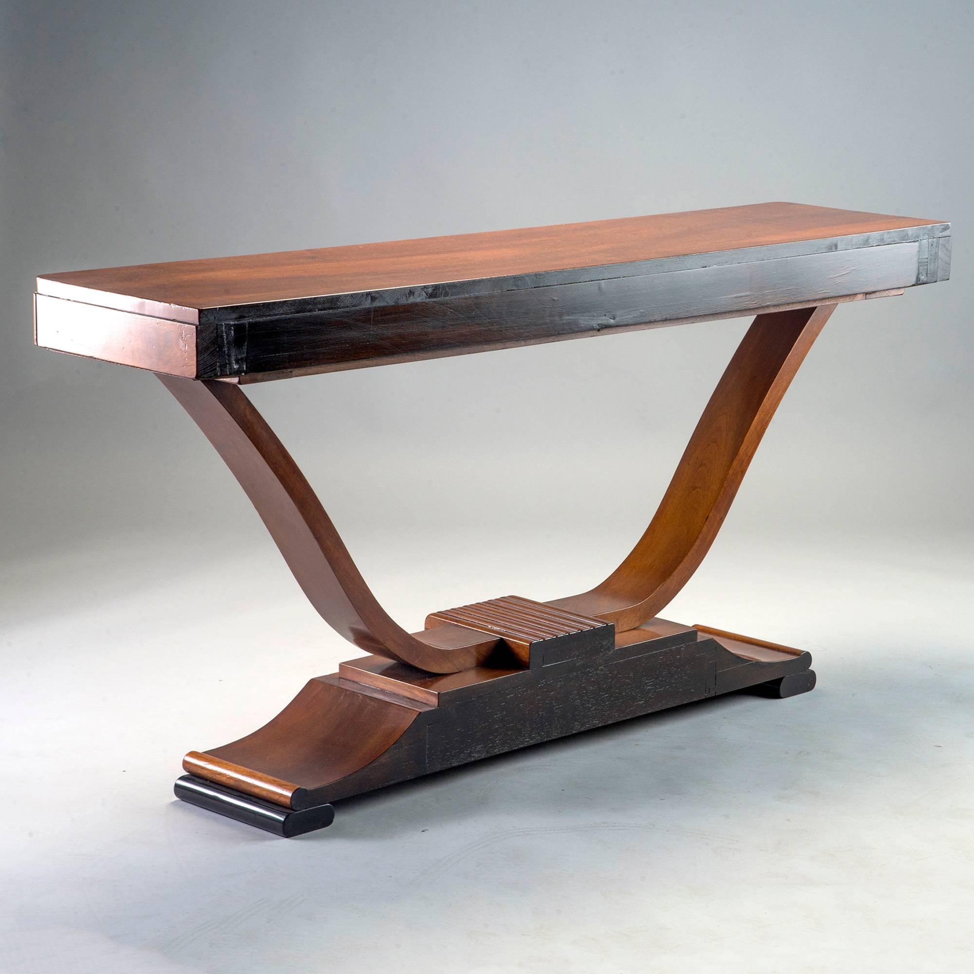 Walnut Art Deco console features a pedestal base with contrasting ebonized feet, open curved supports and a carved ebonized panel depicting a leaping buck, circa 1930s. Found in Belgium.