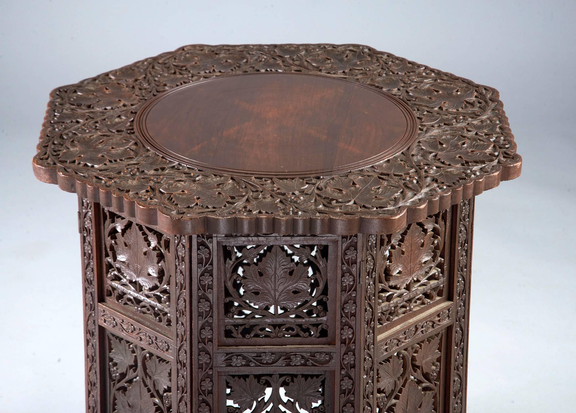 Small Moorish style table has eight-sided base with intricate, open work carved grapes, vines and leaves, Eight-sided table top is removable and base folds flat for easy shipping.