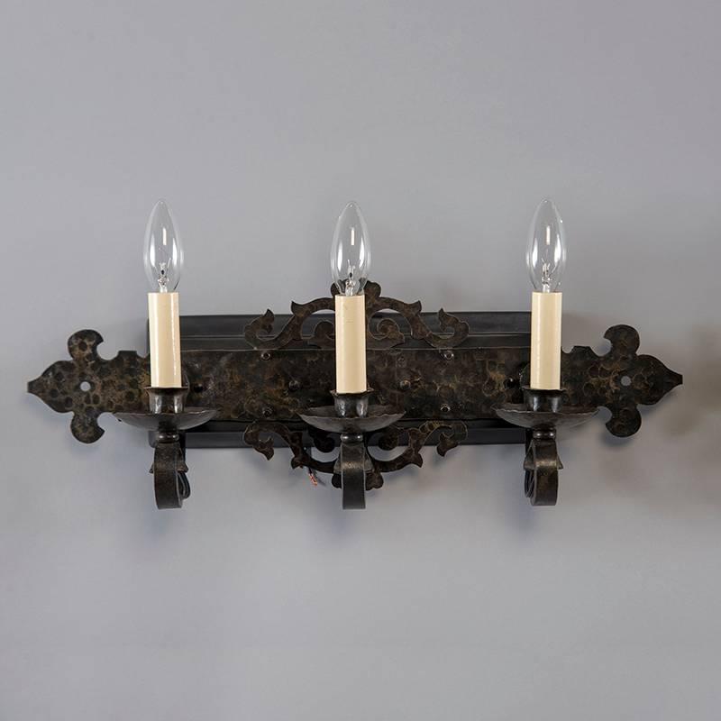 Found in England, this pair of circa 1915 pair of three-light Arts & Crafts era three light sconces have a hammered black iron back plate with candle style lights. New wiring for US electrical standards. Sold and priced as a pair.