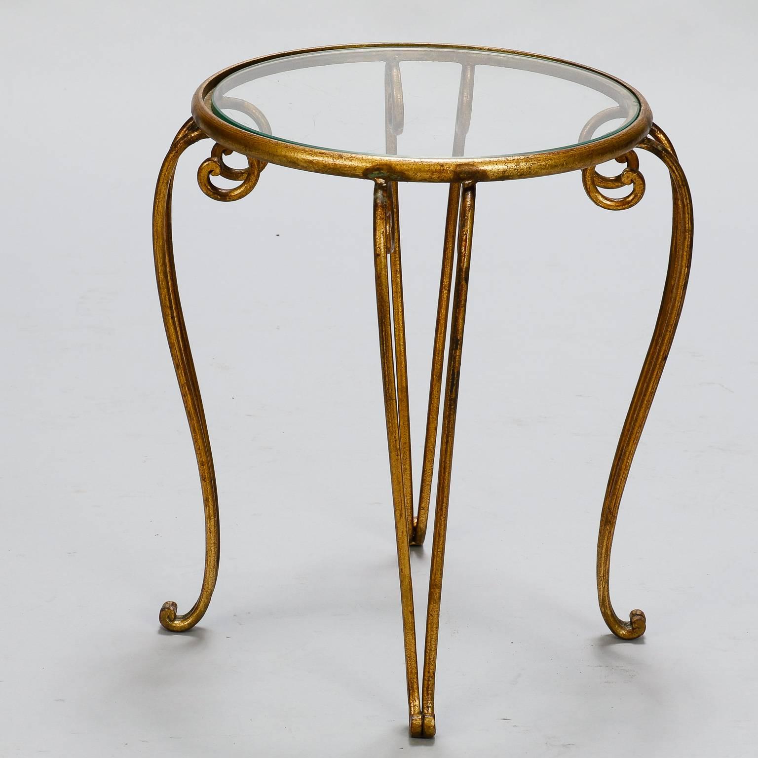 Iron base side table features a gilt finish, cabriole legs and round, clear glass table top, circa 1960s. Excellent vintage condition with some wear consistent with age and use to metal, surface scratches on glass. Table top is 12.5