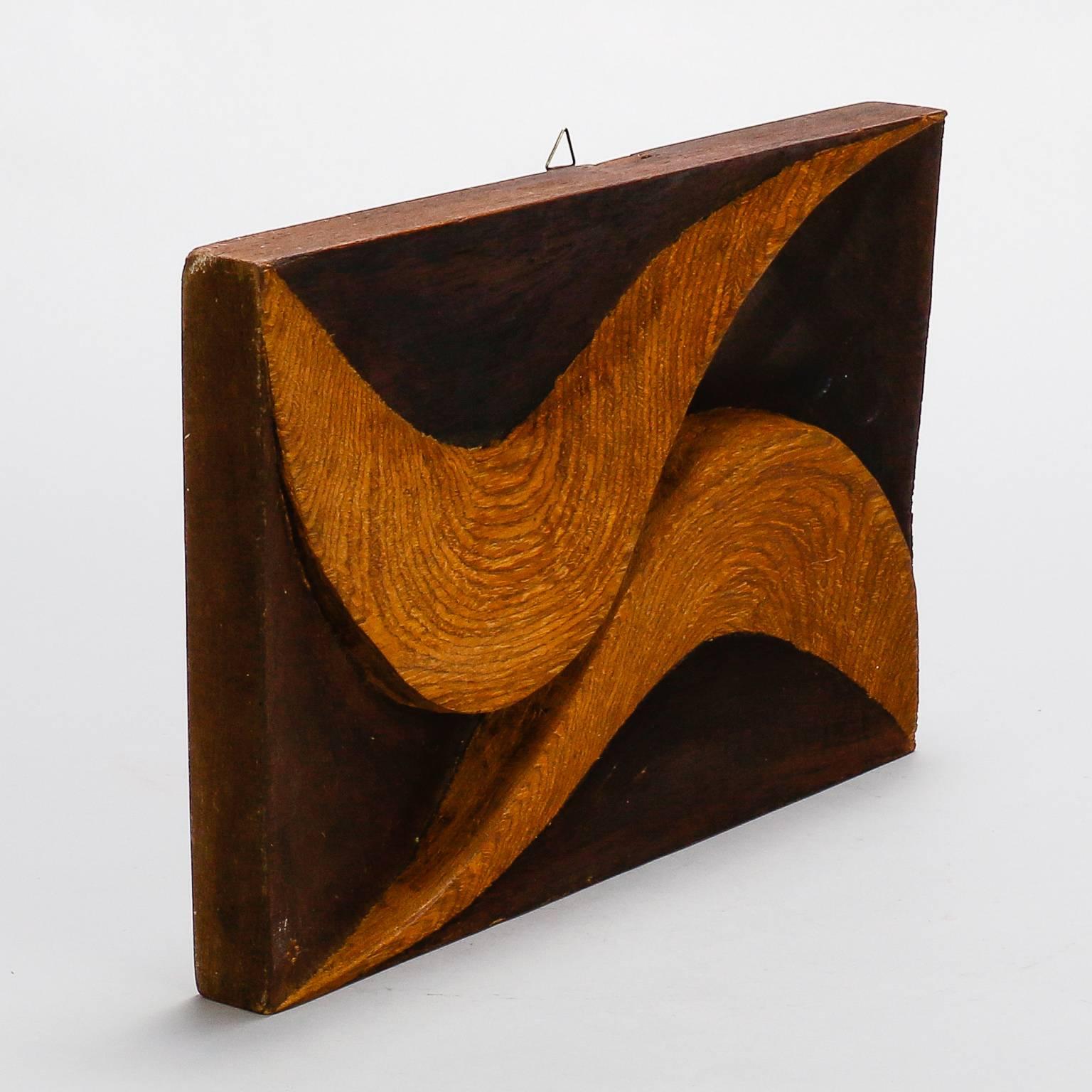 This mid century carved wood plaque by Italian artist Flaviano Laghi dates from approximately 1980 and features two raised light wood swirls with beautiful grain on a contrasting dark wood base.  Additional carved wood pieces from this artist