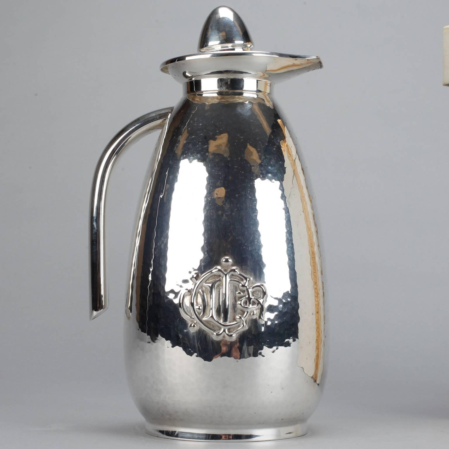 Circa 1970s tall Christian Dior silver plate pitcher with hammered surface texture, stopper, decorative crest in relief at base and original box.