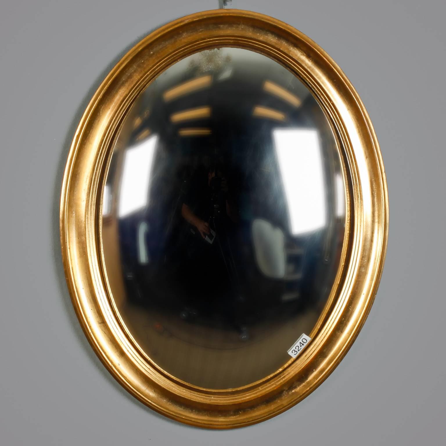Late19th century butler’s mirror found in England features an oval wood frame with gilded finish and convex mirror. 