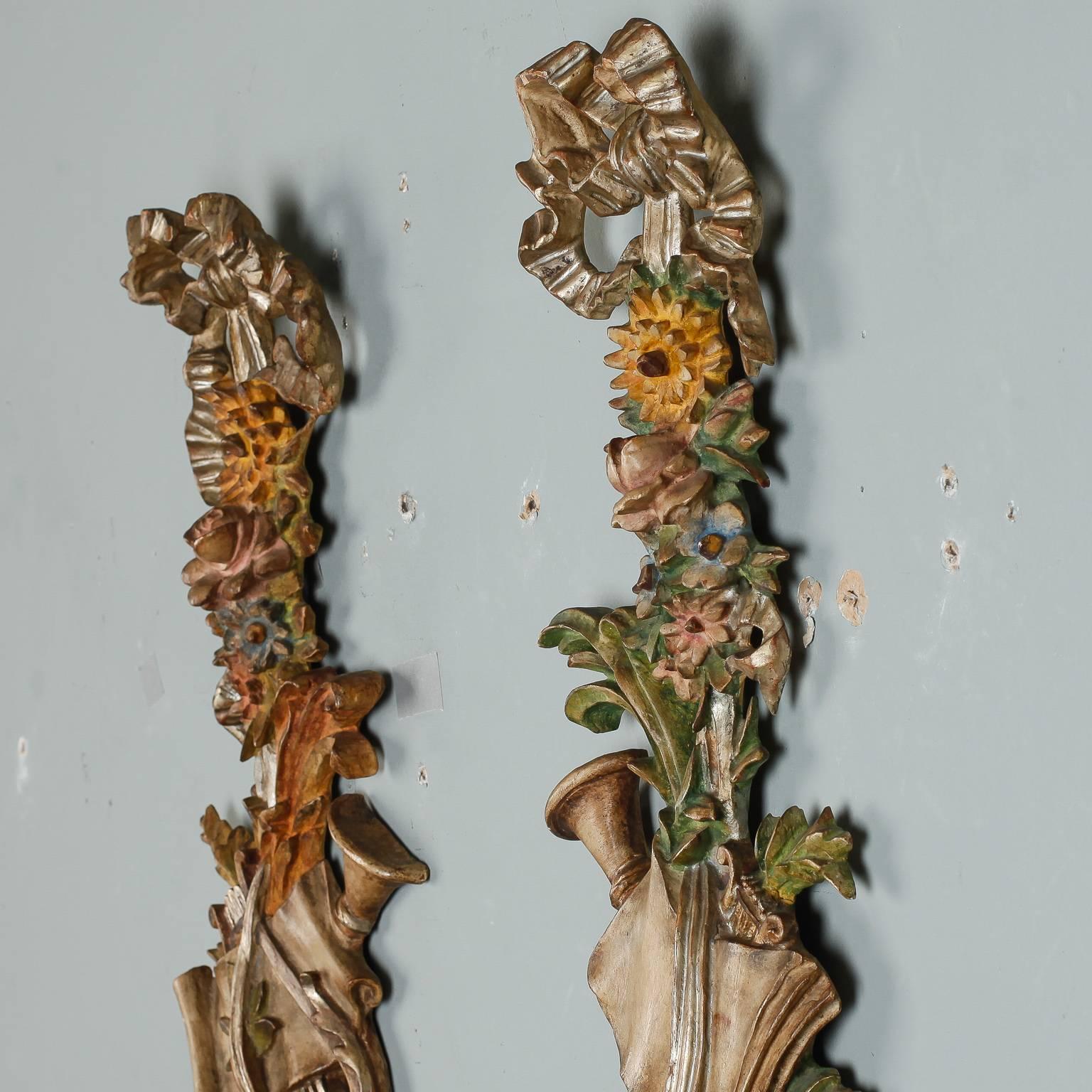 Pair of late 19th century intricately carved wood wall ornaments decorated with harp, Horn, tambourine, ribbons, flowers and leaves to depict Spring and the musical arts. Painted and gilded finish. Sold and priced as a pair. 

 