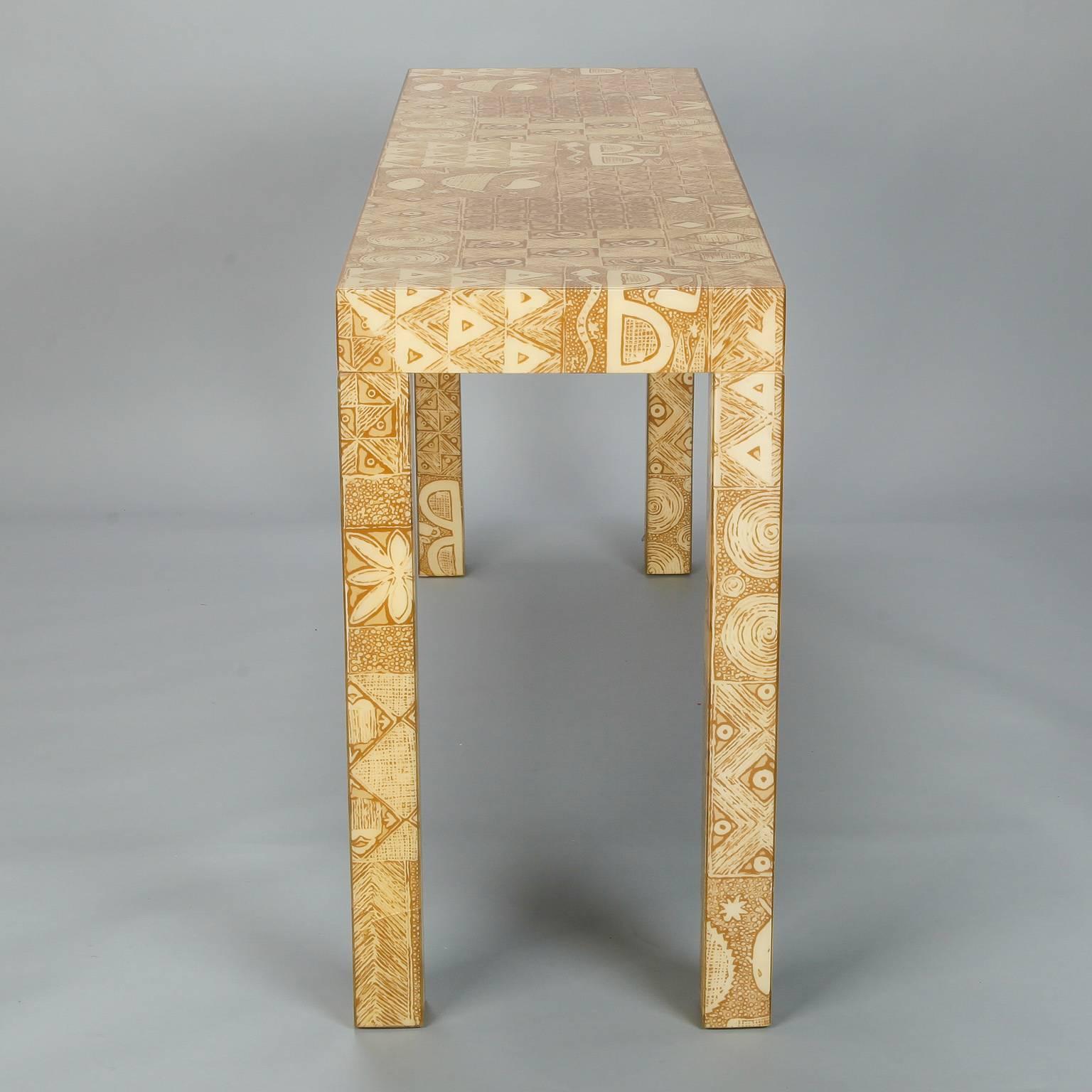 Circa 1970s Parsons style console table has a wood base covered with taupe and ivory printed fabric covered in thick, durable coat of clear acrylic. Unknown maker - found in USA.

 