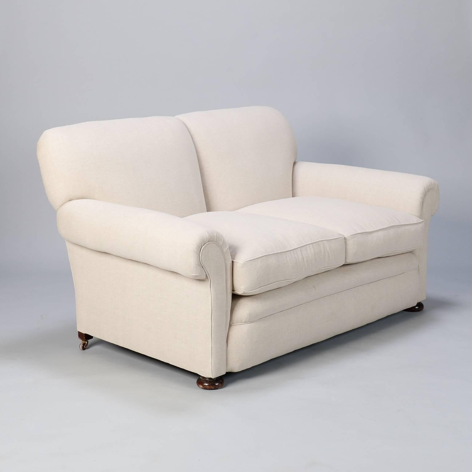 Circa 1930s two seat English club sofa with rolled arms, solid wood frame and coil spring support. Newly upholstered in natural colored Belgian linen. 

Arm Height:  22”   
Seat Height:  19”
Seat Depth:  25”