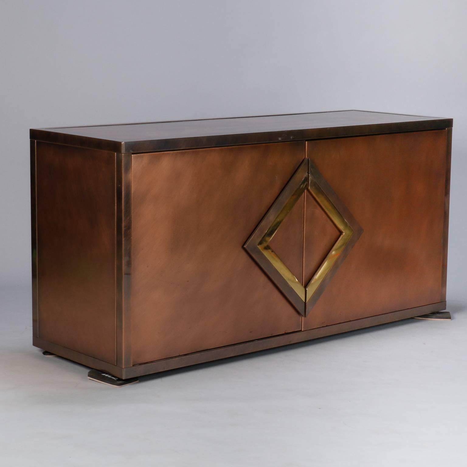 Circa 1970s large mixed metal buffet / server / credenza / cabinet by Maison Jansen. Cabinet has textured copper body with contrasting brass geometric pulls on hinged compartment doors.  Polished metal top, interior shelves. 
