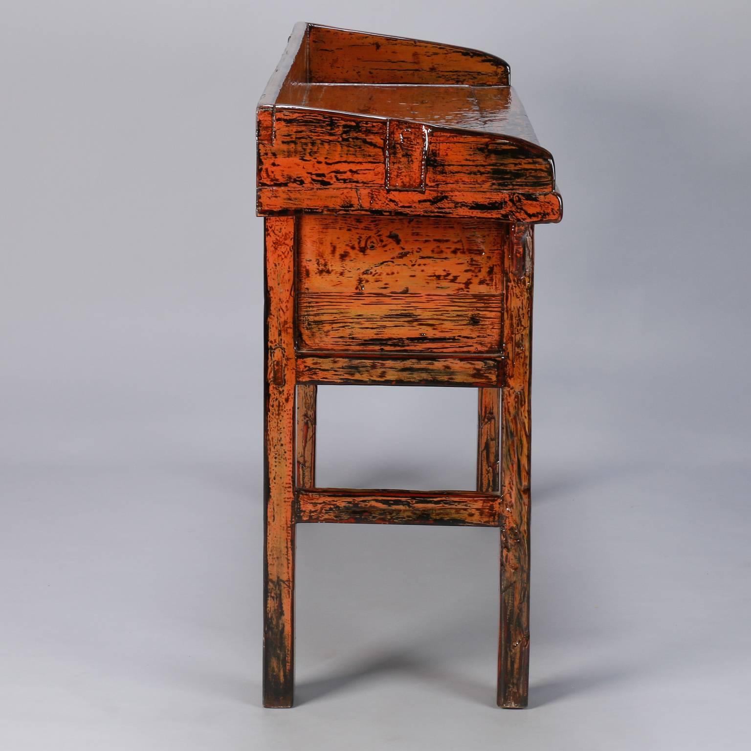 Painted three-drawer Chinese console in dark orange painted and lacquered finish, circa 1900. Worn, primitive paint has fresh coat of lacquer.

 