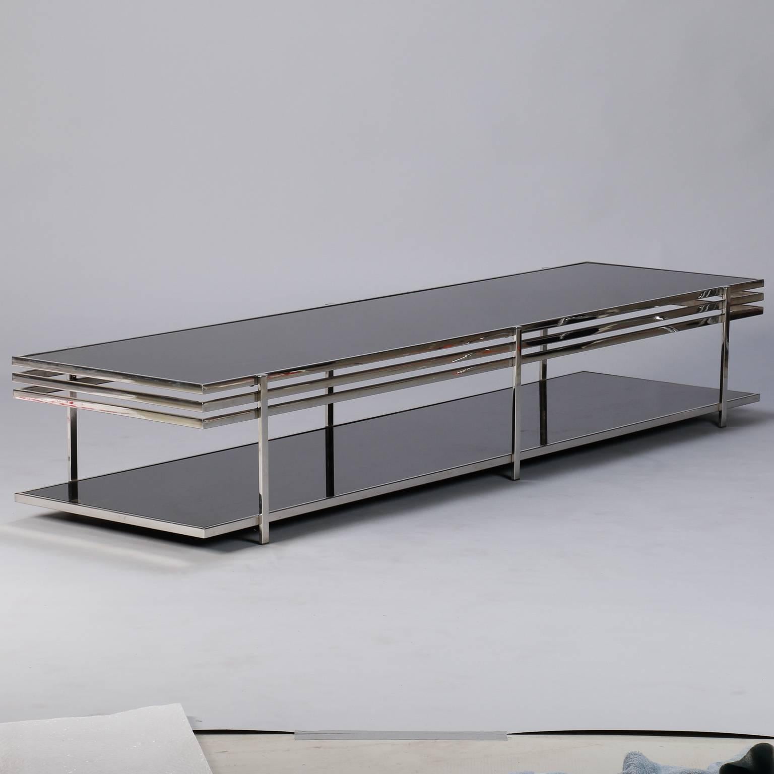 Coffee or cocktail table with chrome frame and black glass, circa 1960s. Top has three flat bands of chrome around top, and a single chrome band around the bottom black glass shelf. No manufacturers marks found - found in Italy. Scattered minor