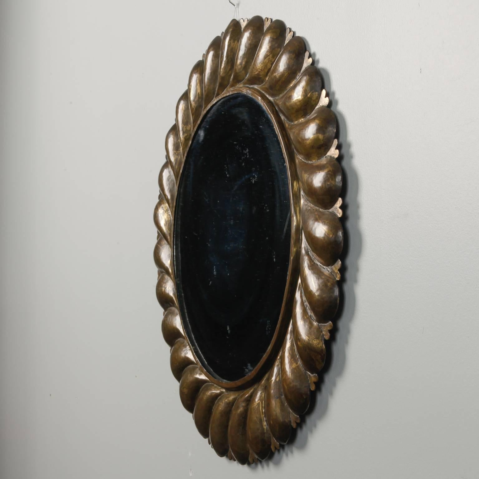 Round mirror framed in brass with a petal-like design in relief, circa 1970s. Found in Italy.