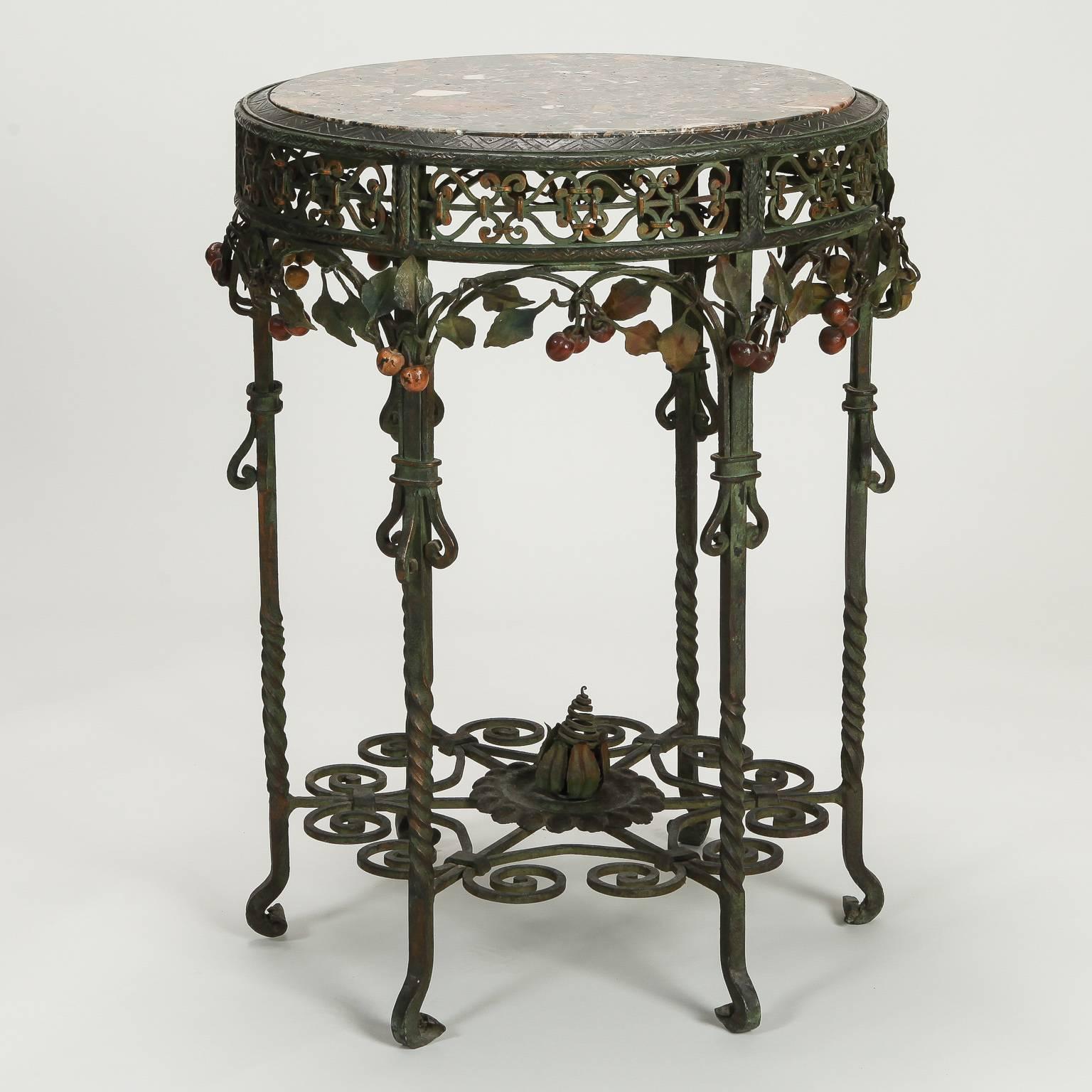 Six legged hand forged iron center table found in Italy, circa 1930s. Round marble table top inset. Apron has elaborate open work design with cherries and leaves adorning the arches. The legs are embellished with scrolls and the center support has
