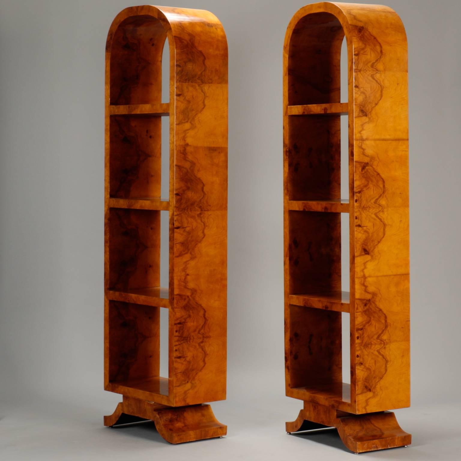 Pair of narrow French etageres in highly polished wood (may be olive wood or some other wood with distinctive burls) with Classic Art Deco style elements. Footed platform base with three fixed shelves and elegant arched tops. Sold and priced as a