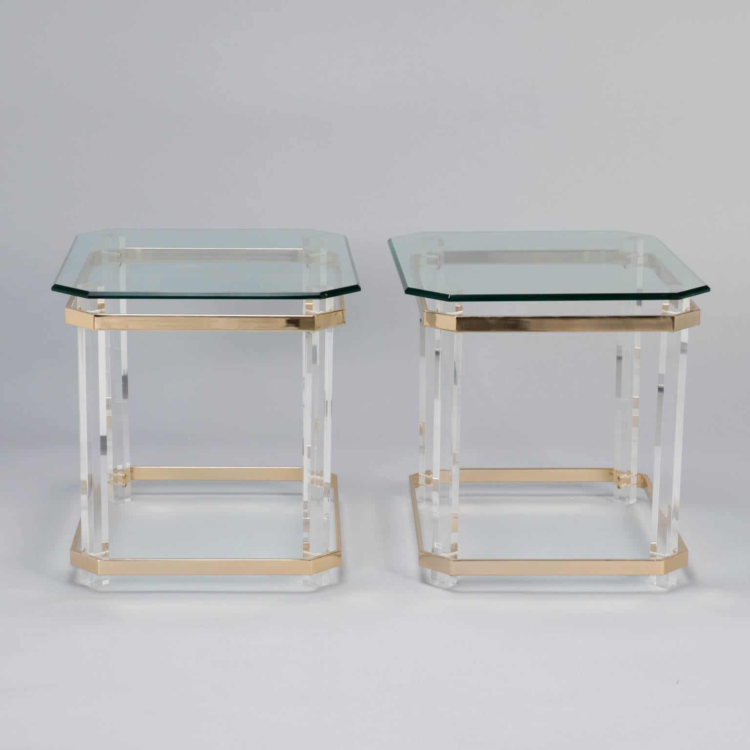 Circa 1970s pair of side or end tables with beveled edge glass tops, clear lucite legs and flat brass plated banding at base and aprons. Excellent vintage condition with very little visible wear. Sold and priced as a pair. 