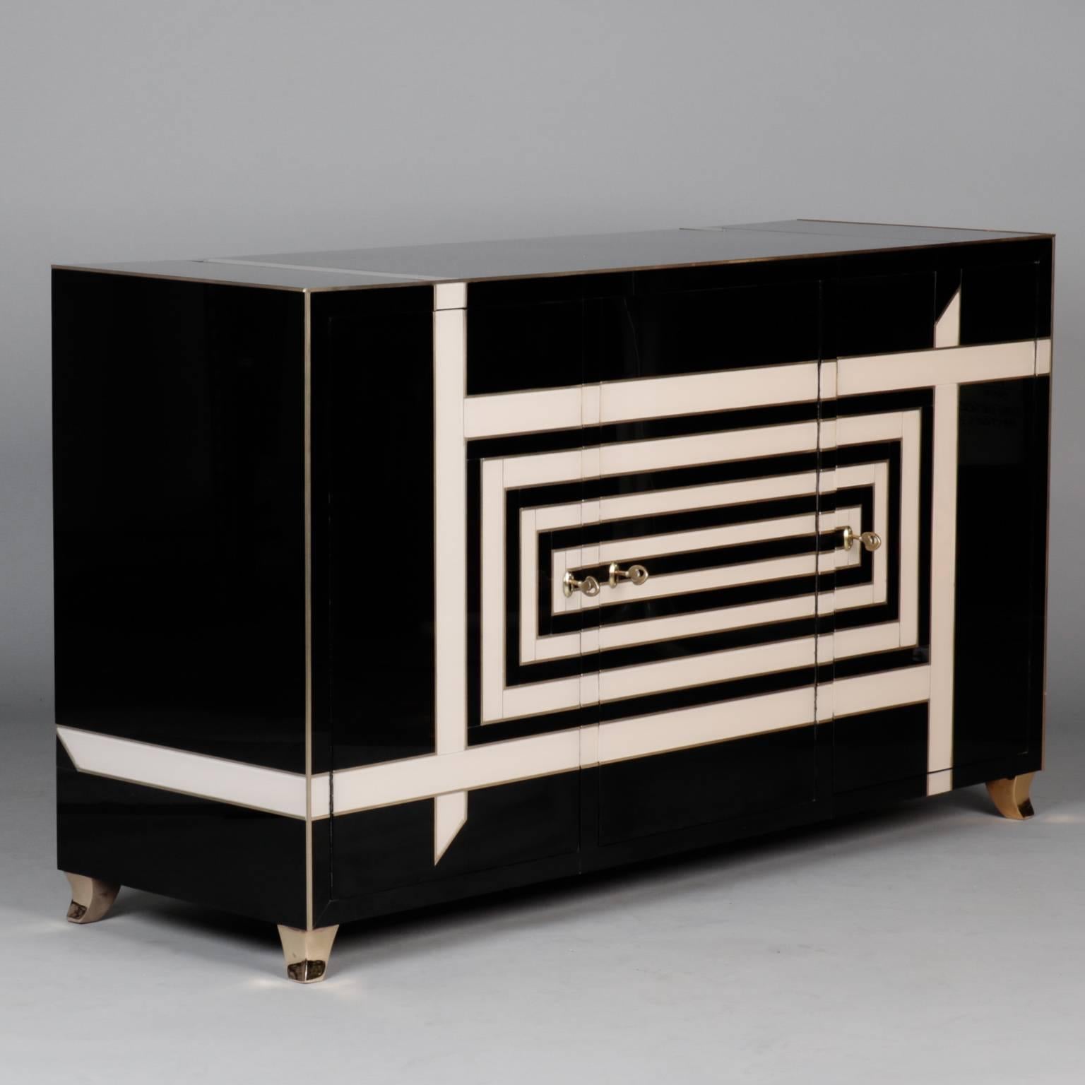 Italian sideboard was custom made for a Venetian luxury hotel, circa 1970s. Wood base sideboard is completely covered in Murano glass panels in a vibrant black and cream graphic design and brass trim. Unknown manufacturer created this top quality