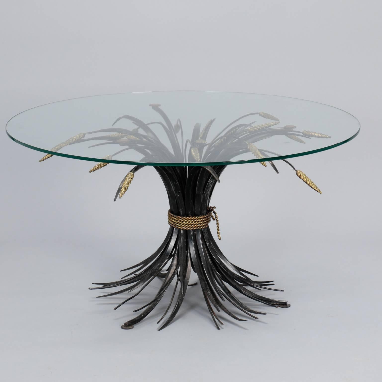Found in Italy, this circa 1940s table has a metal base in the form of wheat sheaf gathered with braided rope. Unusual finish with black stems and contrasting gilded rope and wheat grains. Round glass top is 26” diameter, this base could support a