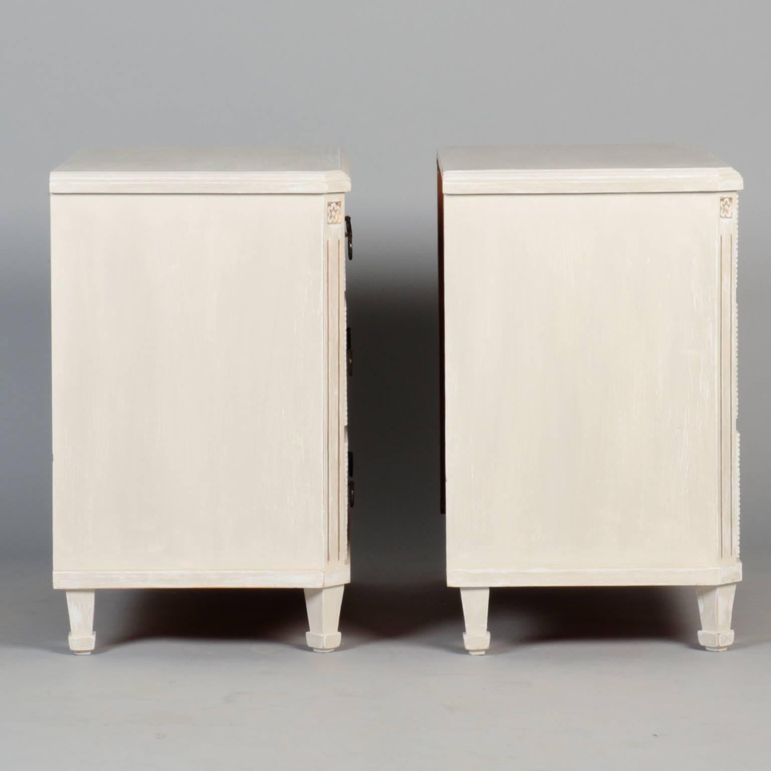 Pair of circa 1930s pair of three-drawer Swedish chests with antique white painted finish. Found in England, these chests have ribbed drawer fronts, decorative carved floral details at the top sides and brass hardware. Versatile size can be used as