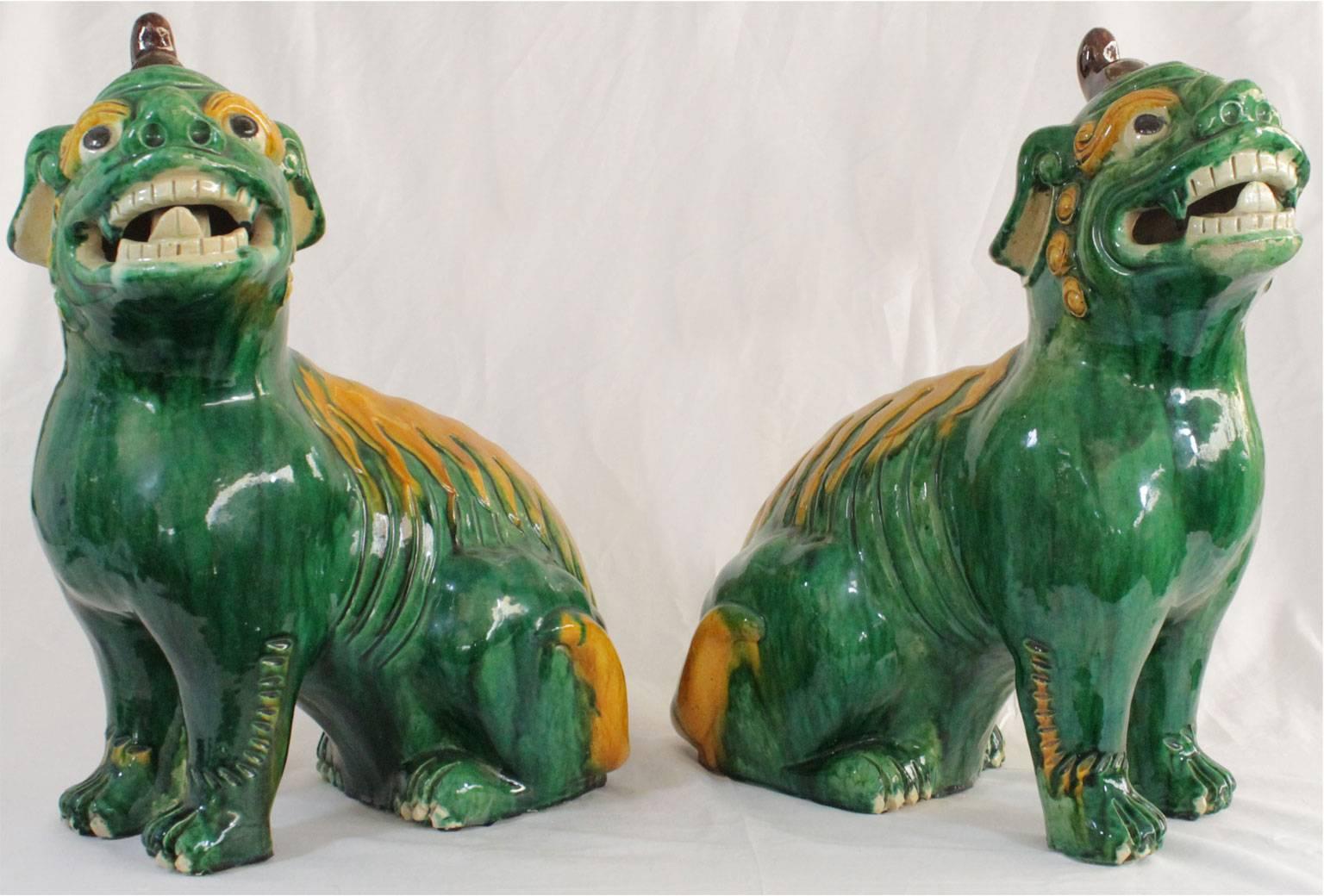 Pair of Qing dynasty foo dogs, of glazed pottery, in the Famille Verte et Jaune palette, each a freestanding, wild looking mythical dog, with open mouth, teeth, extended tongue, bulging eyes and a horn.

Stock ID: D8755.