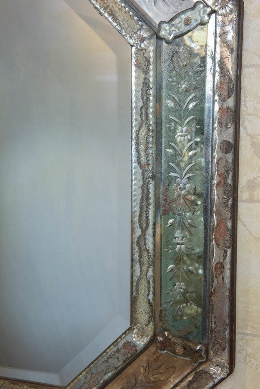 Venetian-style beveled, etched and cut glass octagonal mirror, the central beveled plate framed by cut foliate scroll and banded plates, with rosette-headed nails of glass, surmounted by foliate scrolling pediment.