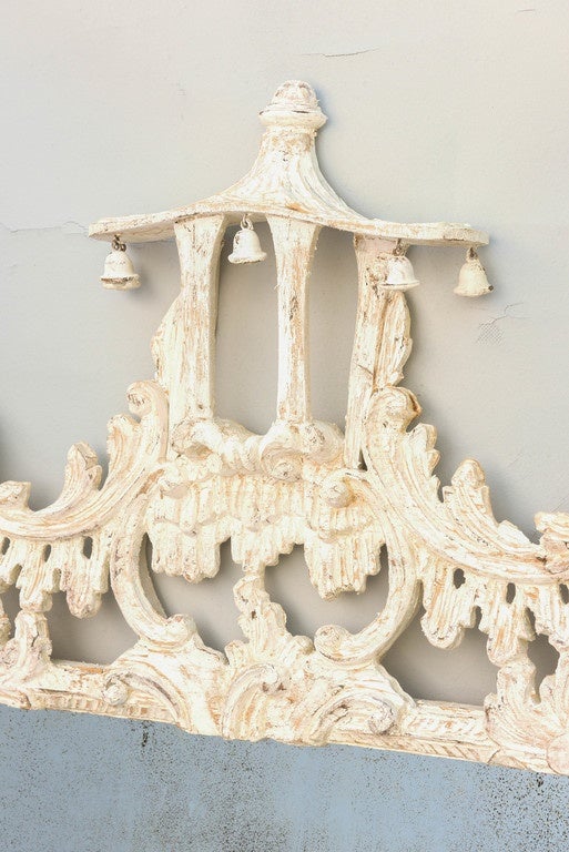 Pair of mirrors, painted white with distressed finish; in Brighton Pavillion taste, having an elaborate hand carved, pierced frame, surmounted by a pagoda, and trimmed in bells, surrounded by C-scrolls and foliate reliefs, spotted mirror plate.