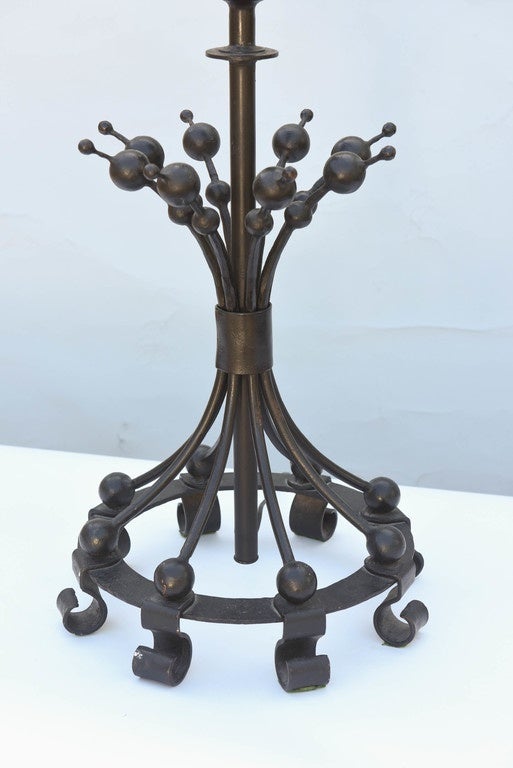 Unusual lamp, of black painted iron, its central standard surmounted by a large round knob, surrounded by a grouping of splayed spires ending in graduated balls, joined by circular base and scrolling feet.

Stock ID: D6568