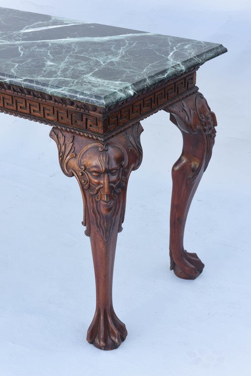 Console table, of walnut, having a later rectangular top of green marble, on apron lavishly carved with gadrooning, over Greek-key meander, raised on unusual cabriole hock-legs, with stylized knees of C-scrolls creating a bearded mask, ending in paw