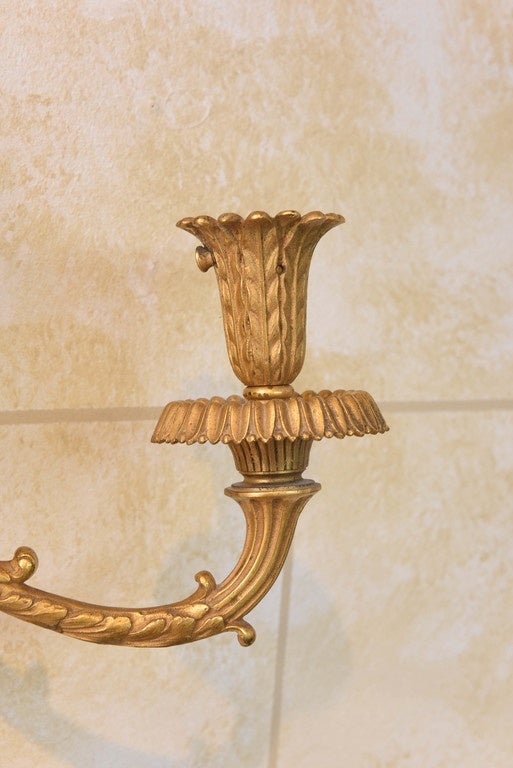 Finely chased pair of sconces, of gilt bronze, in Louis XVI taste, each backplate containing three mirrors in egg-and-dart frames, joined by scrolling acanthus, and rosettes, surmounted by a bow, double S-scroll acanthine candlearms, finished in