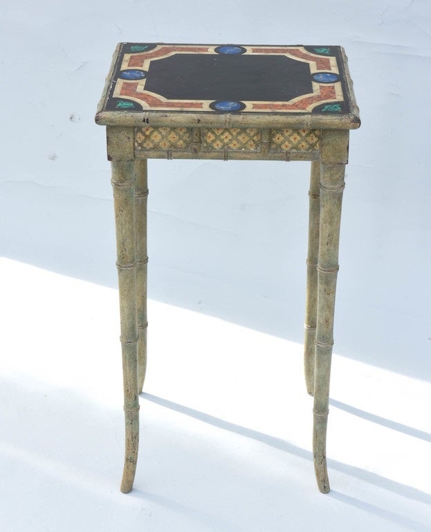Accent table, having a square top, handpainted as pietra-dura specimen marbles in geometric pattern, on green painted base, with natural wear, its fielded apron decorated with quatrefoil, cross-hatch panels, on faux bamboo splayed legs.