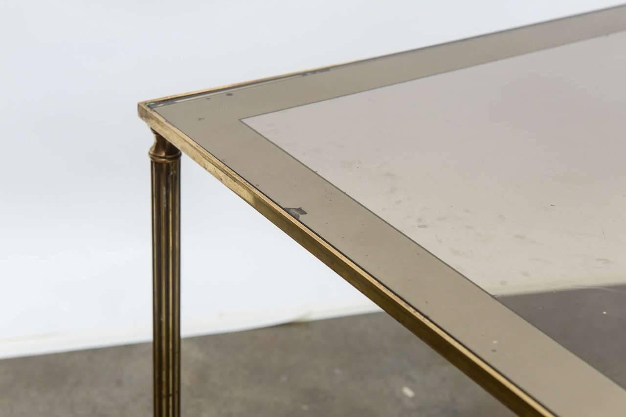 Surtout de table style cocktail table, having rectangular main table, flanked by a pair of demilune accent tables, with polished brass frame, raised on reeded legs, ending in touipe feet. All tables with original glass tops, accented with mirrored