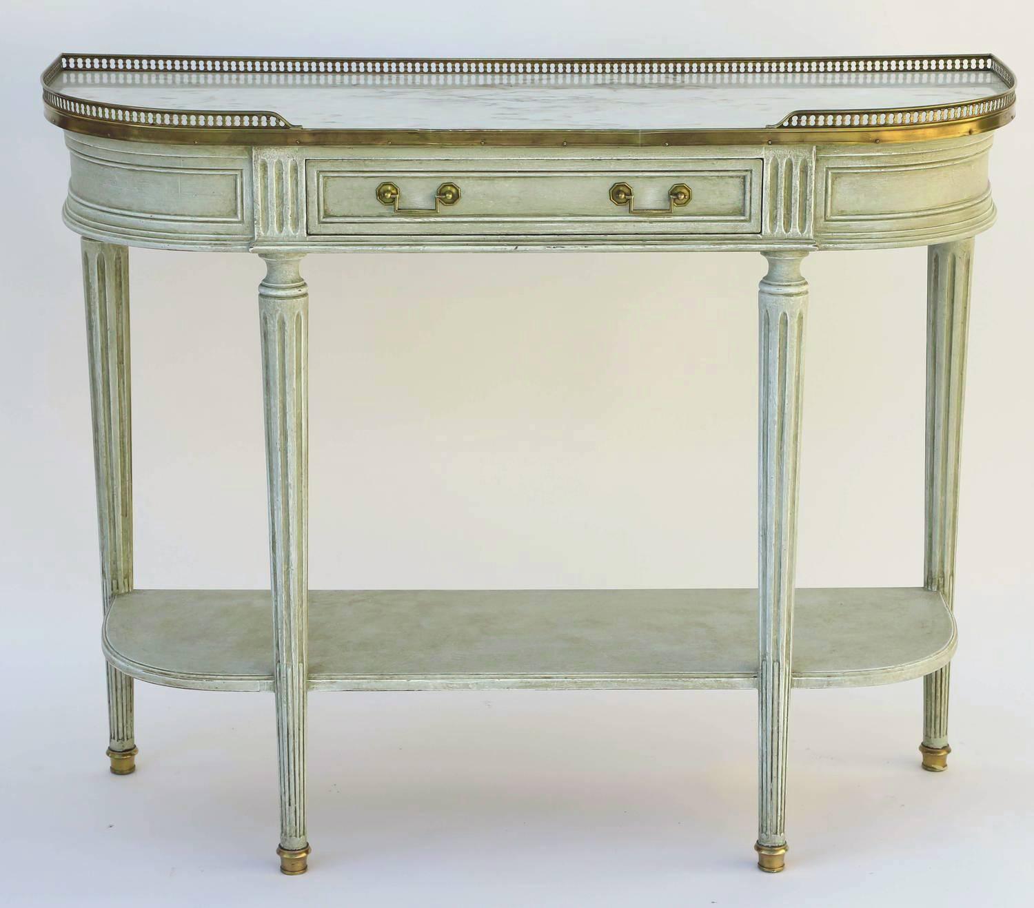 Console desserte, in the Louis XVI style, having a "D-shaped" top of marble, with 3/4 pierced gallery of brass, on fielded apron, with single frieze drawer, raised on round, tapering, fluted legs, joined by shelf stretcher, ending in cup