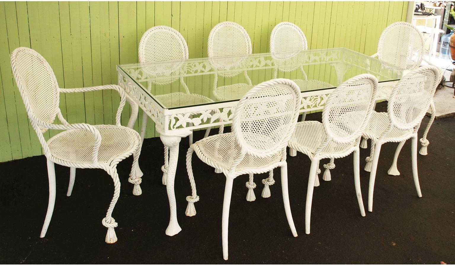 Patio dining table and chairs, the table having a rectangular glass top on white painted frame, its pierced apron decorated with undersea motifs, raised on whimsical cabriole legs lined with fish scales; the six side chairs, and two armchairs, by