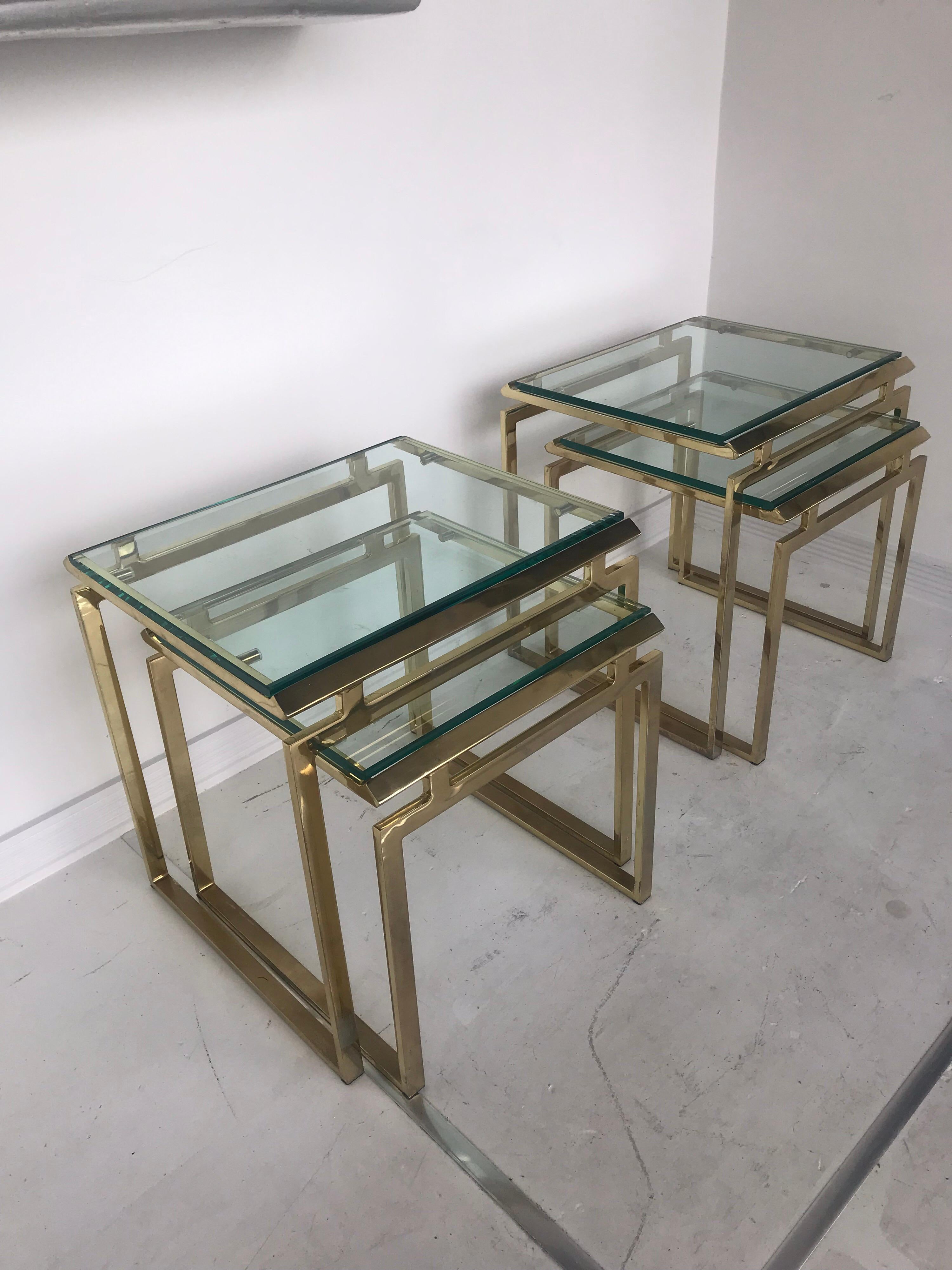 Pair of modernist nesting tables in brass with beveled glass tops. The set is two larger tables and two smaller tables which nest perfectly under the larger ones.
