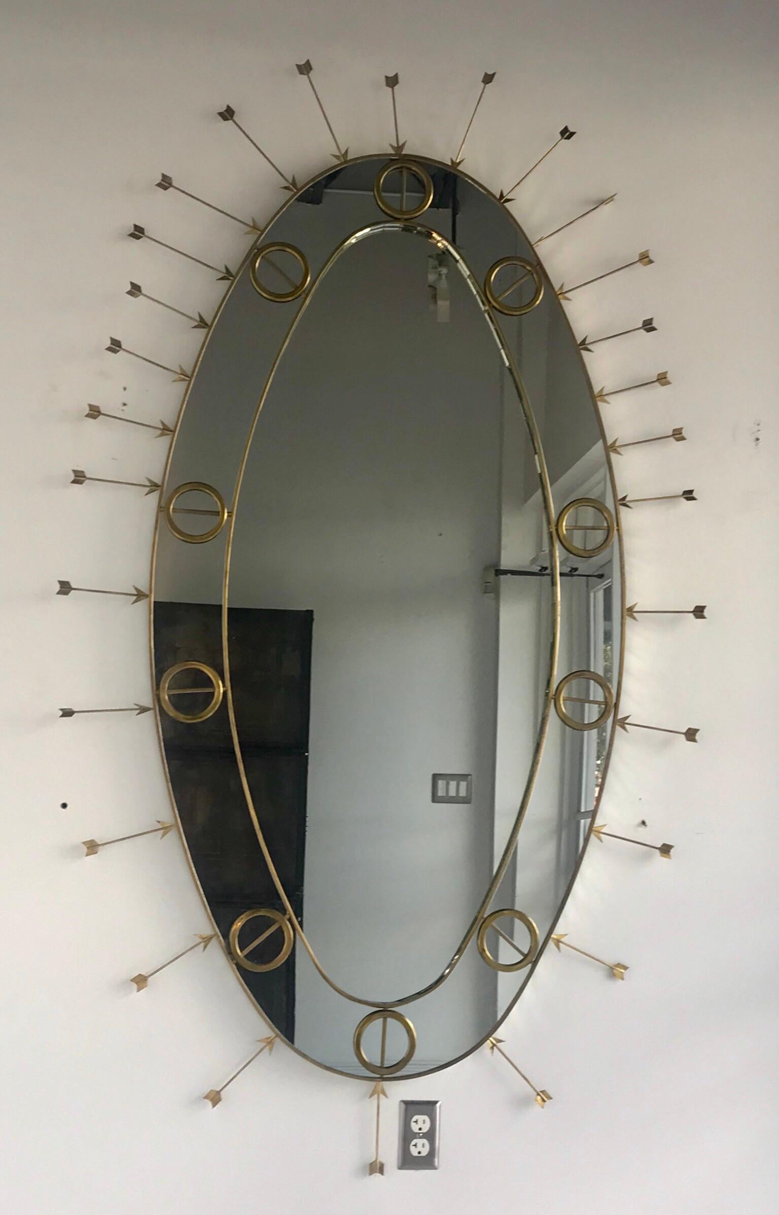 Large oval mirror with brass details and arrows.