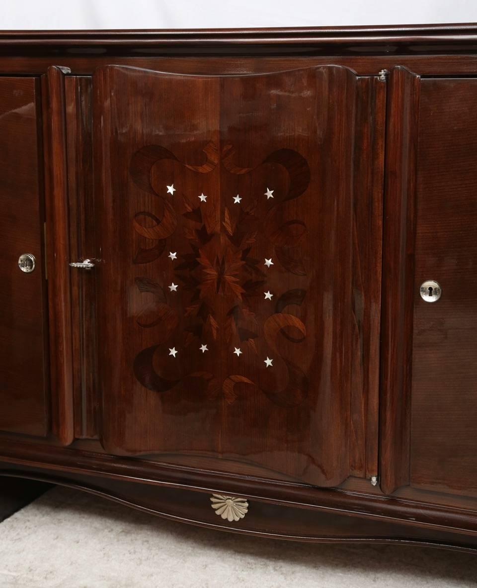 The exotic wood, nickel dipped bronze trim and hardware, plus the Marquetry and mother-of-pearl inlay combination create a Luxurious French Art Deco Buffet in the manner of Jules Leleu.