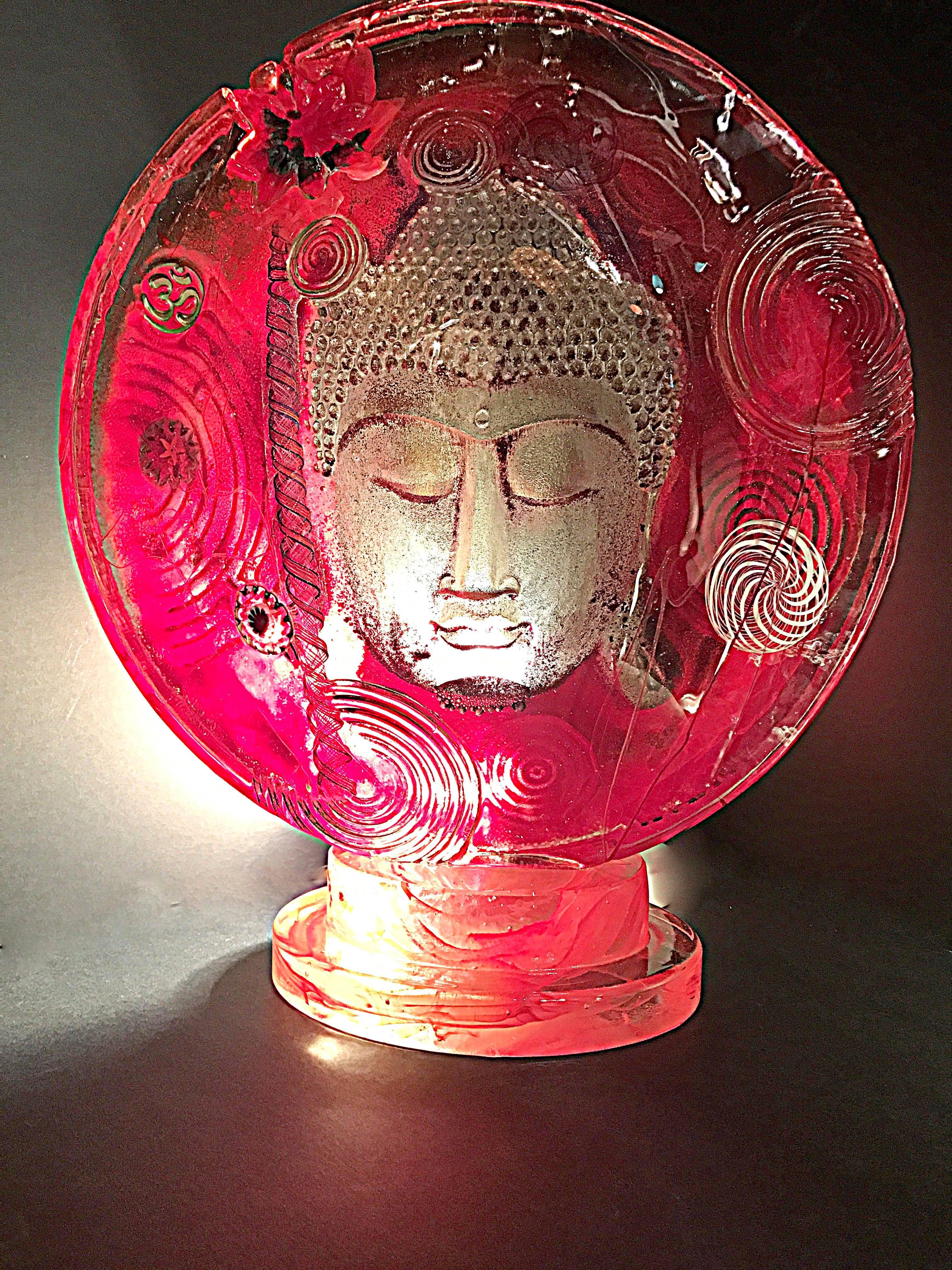 Various Faces of Buddha are depicted using very thick glass casting with layered color inclusion which creates the floating face deep in meditation. The faces are dusted with silver or gold leaf which gives a gorgeous glow to each piece. 
Large