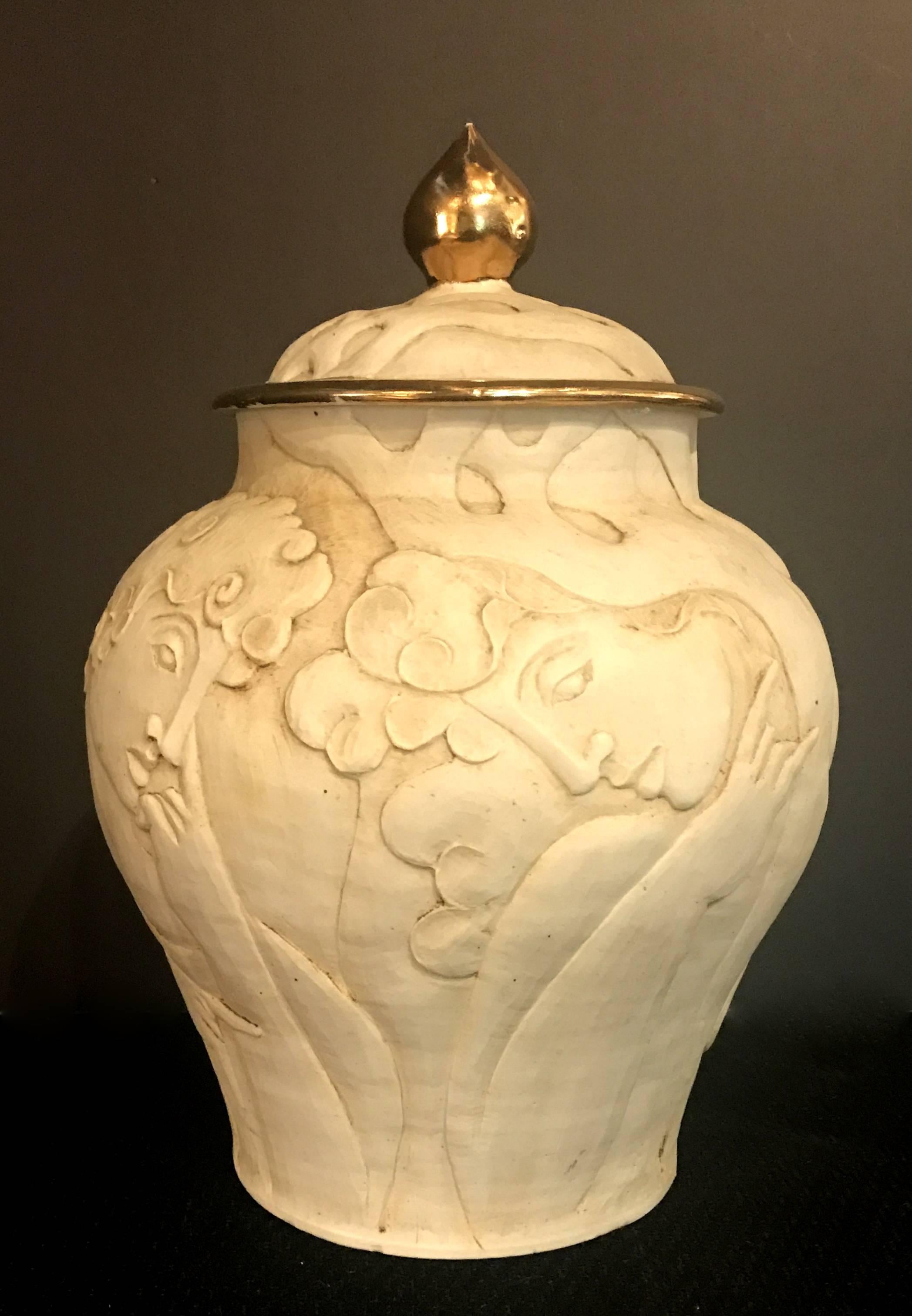 Unique Art Deco urn of carved male busts, vines and flowers in porcelain bisque. The lid is trimmed in gold. The urn is in great original condition.