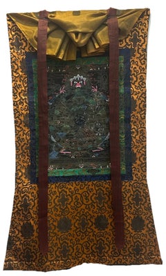 Thangka tibetana de mediados del siglo XX con la Rueda de la Vida en negro y dorado, con brocado de seda