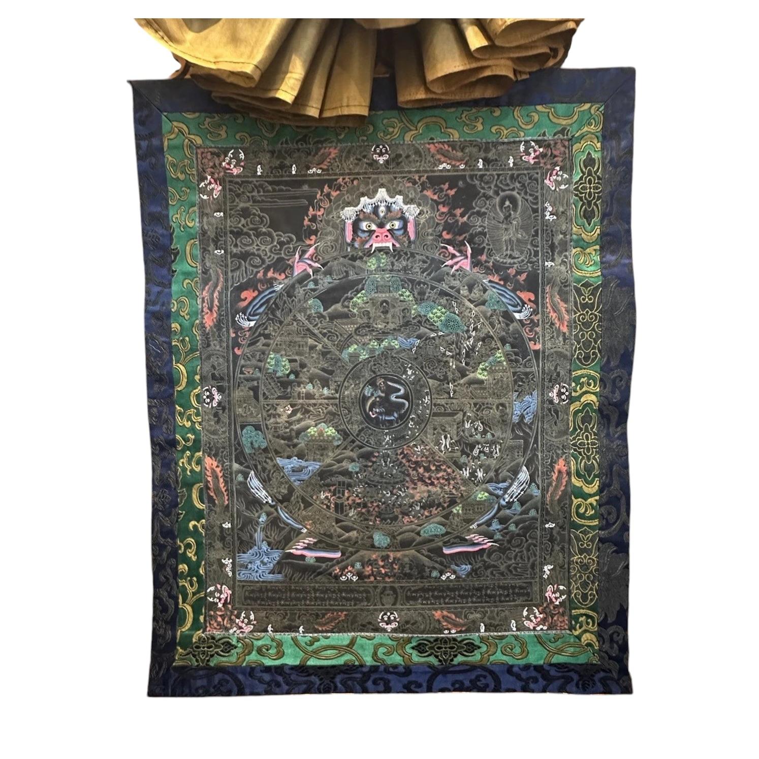 Thangka tibétaine représentant la « Roue de la vie », datant du milieu du XXe siècle, en noir et or, avec brocart de soie