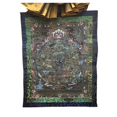 Thangka tibetana de mediados del siglo XX con la Rueda de la Vida en negro y dorado, con brocado de seda