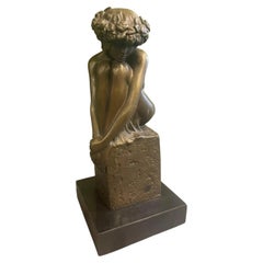 Figurine féminine assise en bronze, ornée d'une guirlande, sur un socle en marbre