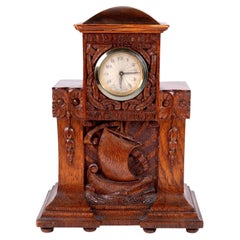 Horloge de cheminée ancienne en chêne sculpté de style Arts & Crafts, ornée d'un motif représentant un bateau-dragon