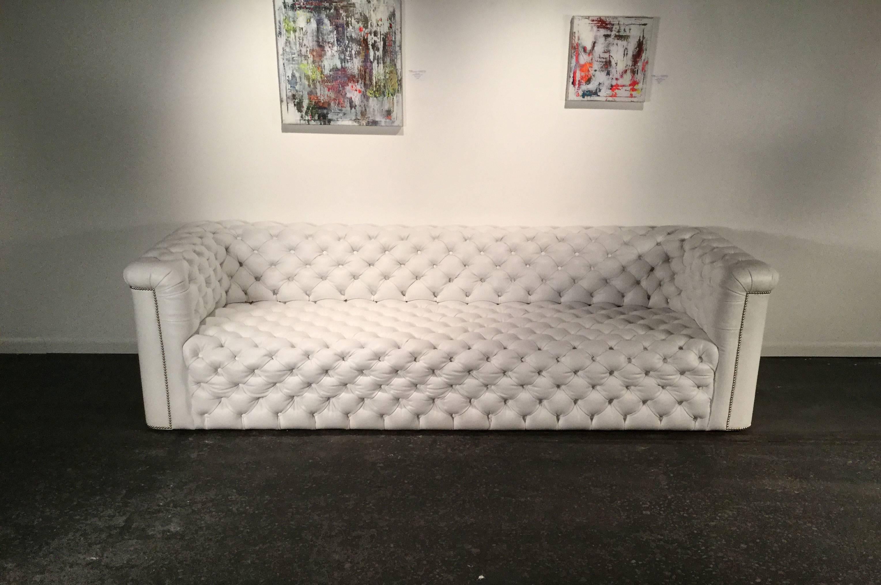 Modern Chesterfield sofa. Amazing tight button tufting with squared off arms and backrest. Nickel nailhead detail all in white leather.