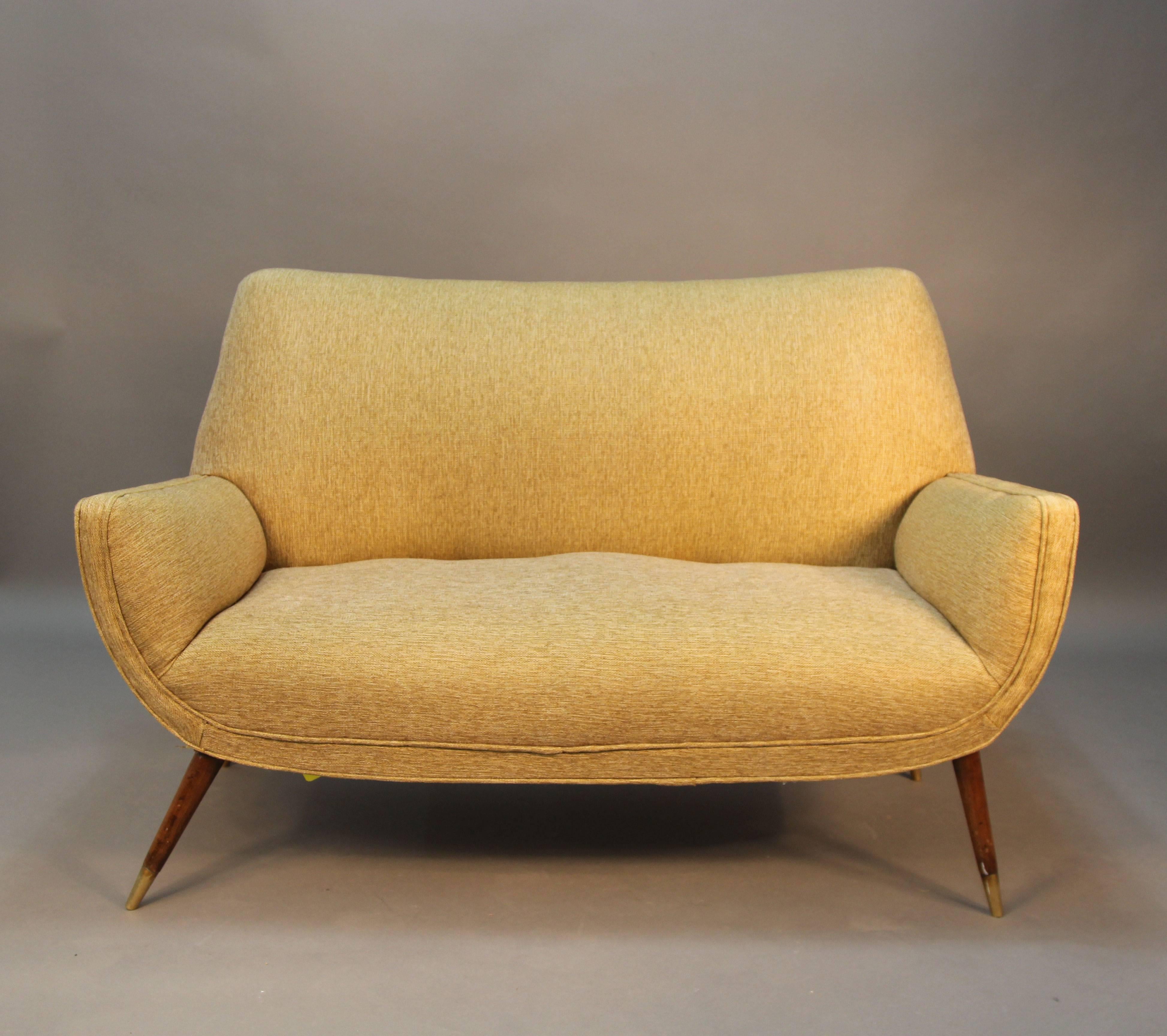 1950s Modern upholstered loveseat with walnut flared legs and brass sabots.
