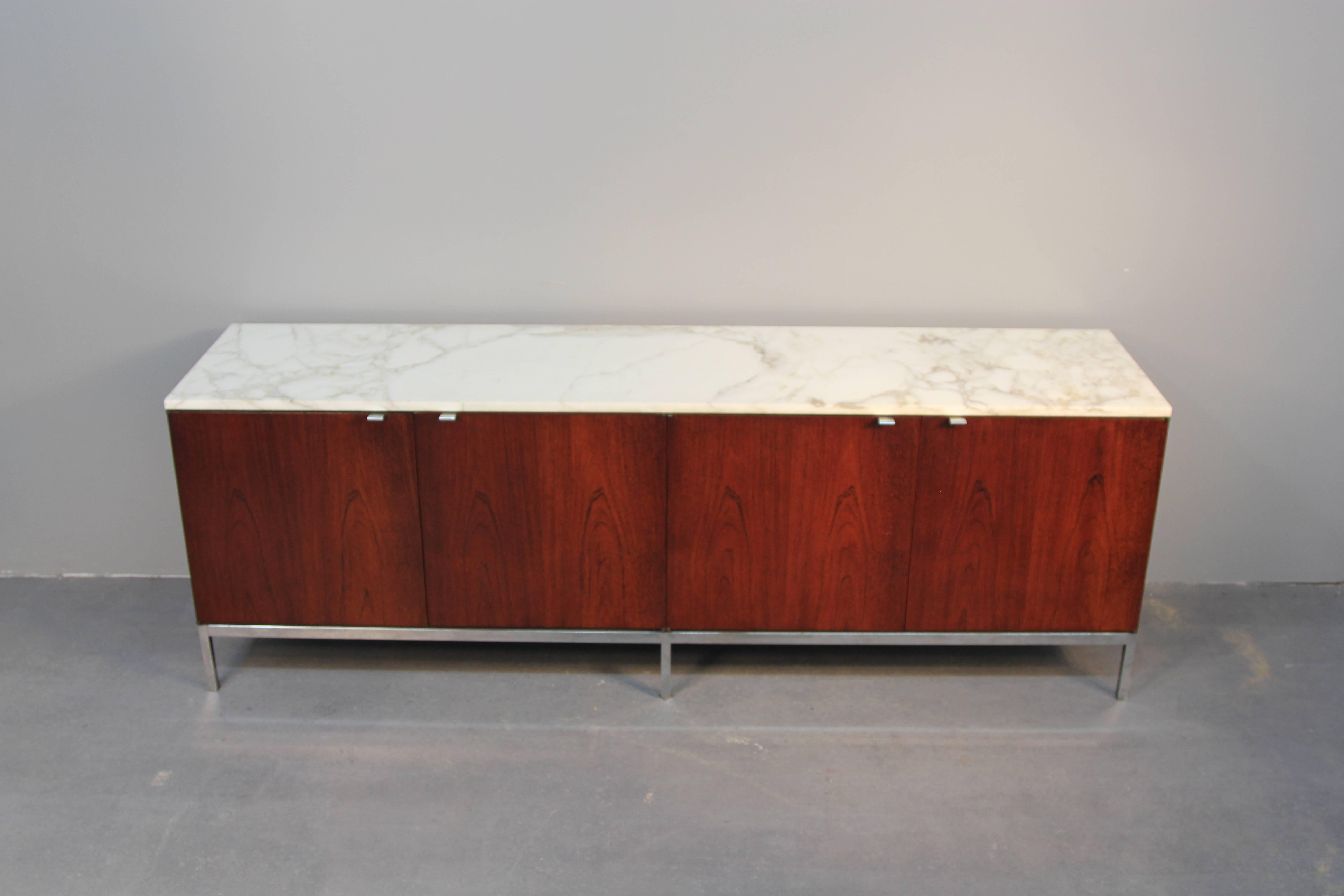 Amazing Carrara marble-top Florence Knoll credenza. Rosewood cabinet with two sets of doors, chrome hardware and base. Two pullout silverware drawers, dividers and pull-out platform on right side. Makes a great sideboard, cabinet, or entertainment