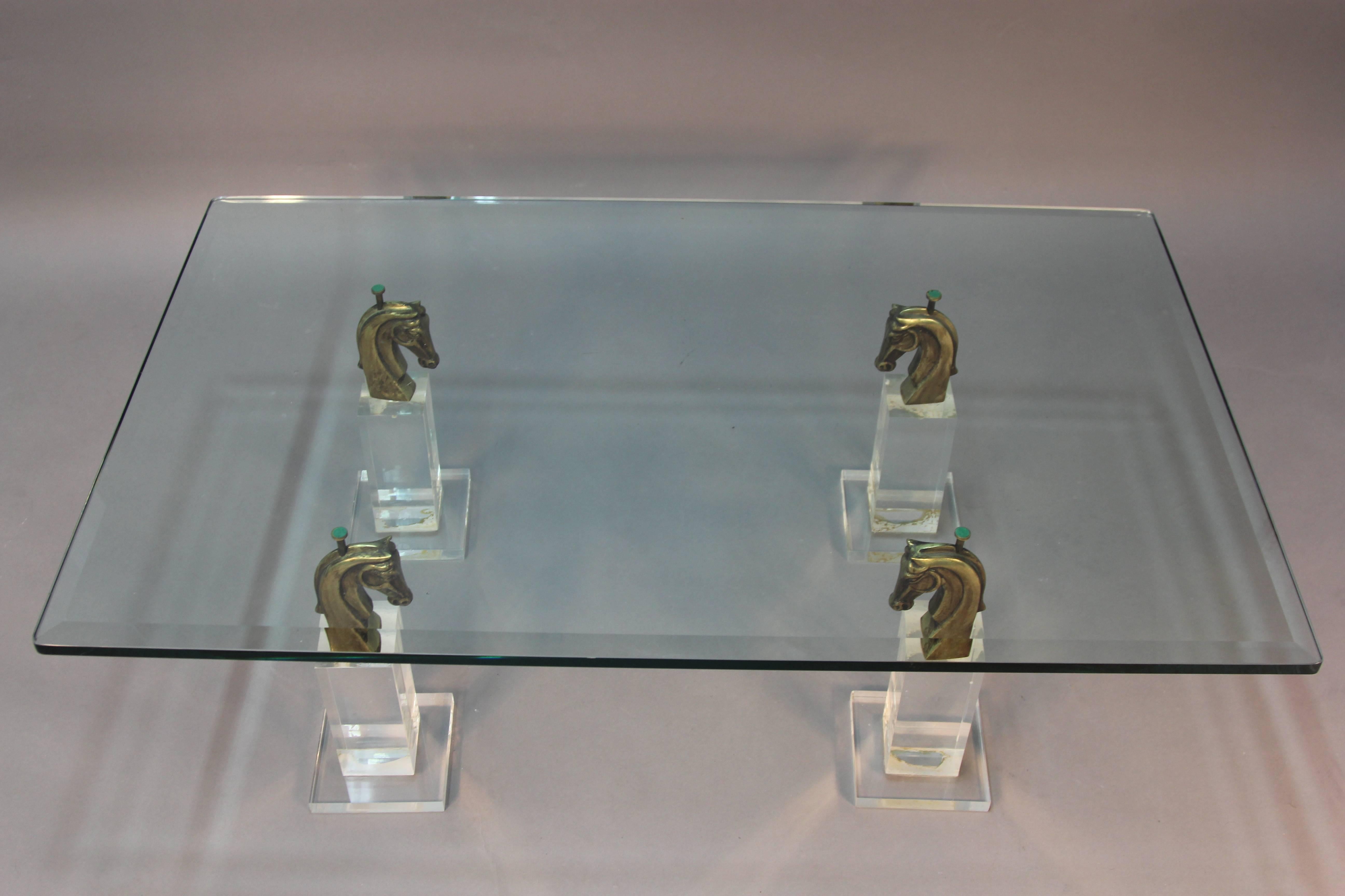 A rare design, Lucite and beveled glass coffee table with bronze patinated horse head sculptures.