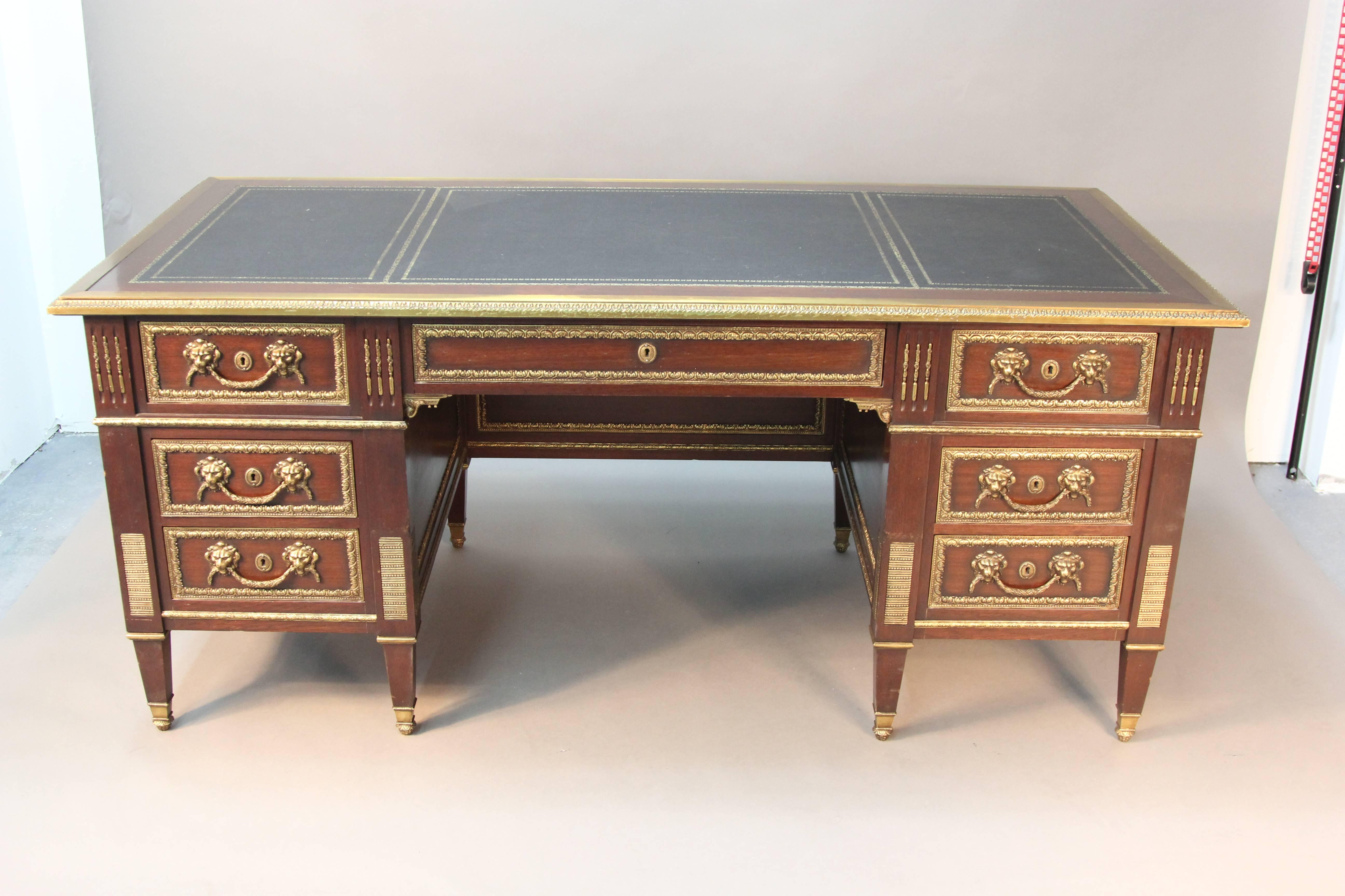 A large antique French executive desk adorned with gilt bronze mounts and figurative animal head drawer pulls. Gilt embossed leather top.  Very finely cast dore bronze mounts.