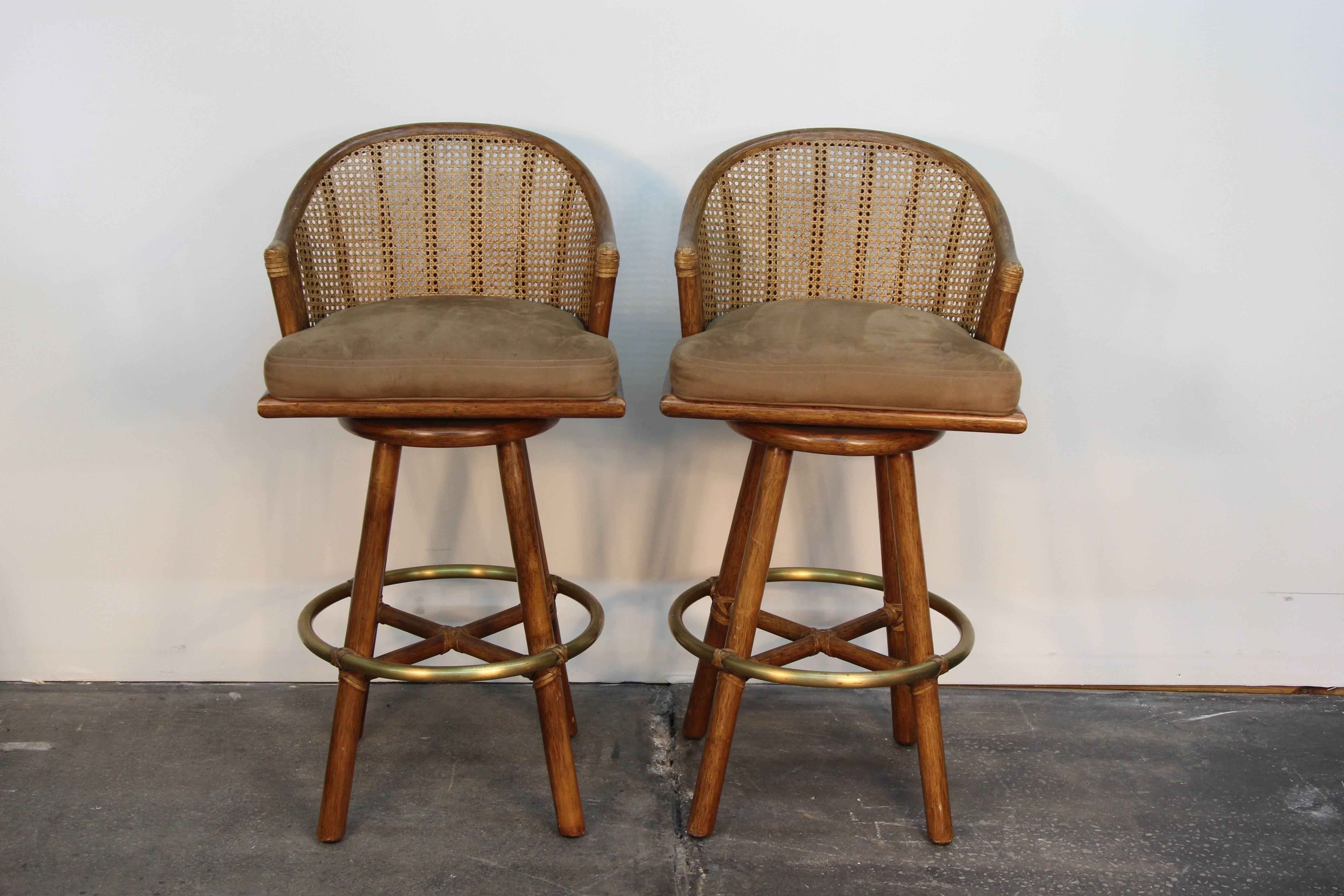 Two Mid-Century rattan swivel bar stools with rattan backs, leather bindings and brass foot rest.