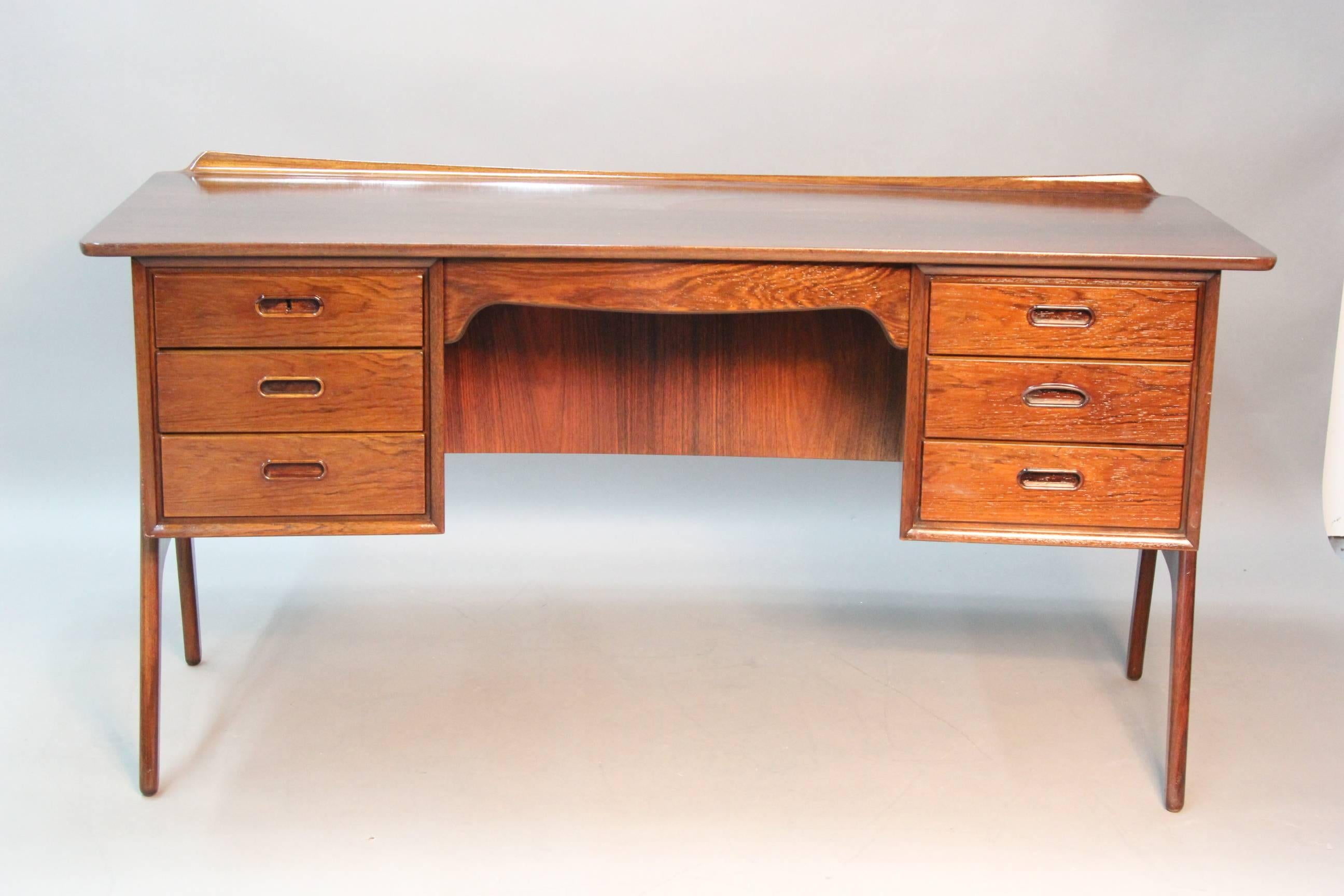 Incredible style and unique shape. This amazing Danish rosewood desk has a front bookshelf or display area, very interesting arched legs and side drawers. Brand newly refinished. With branded mark and paper label. Incredible and rare piece.