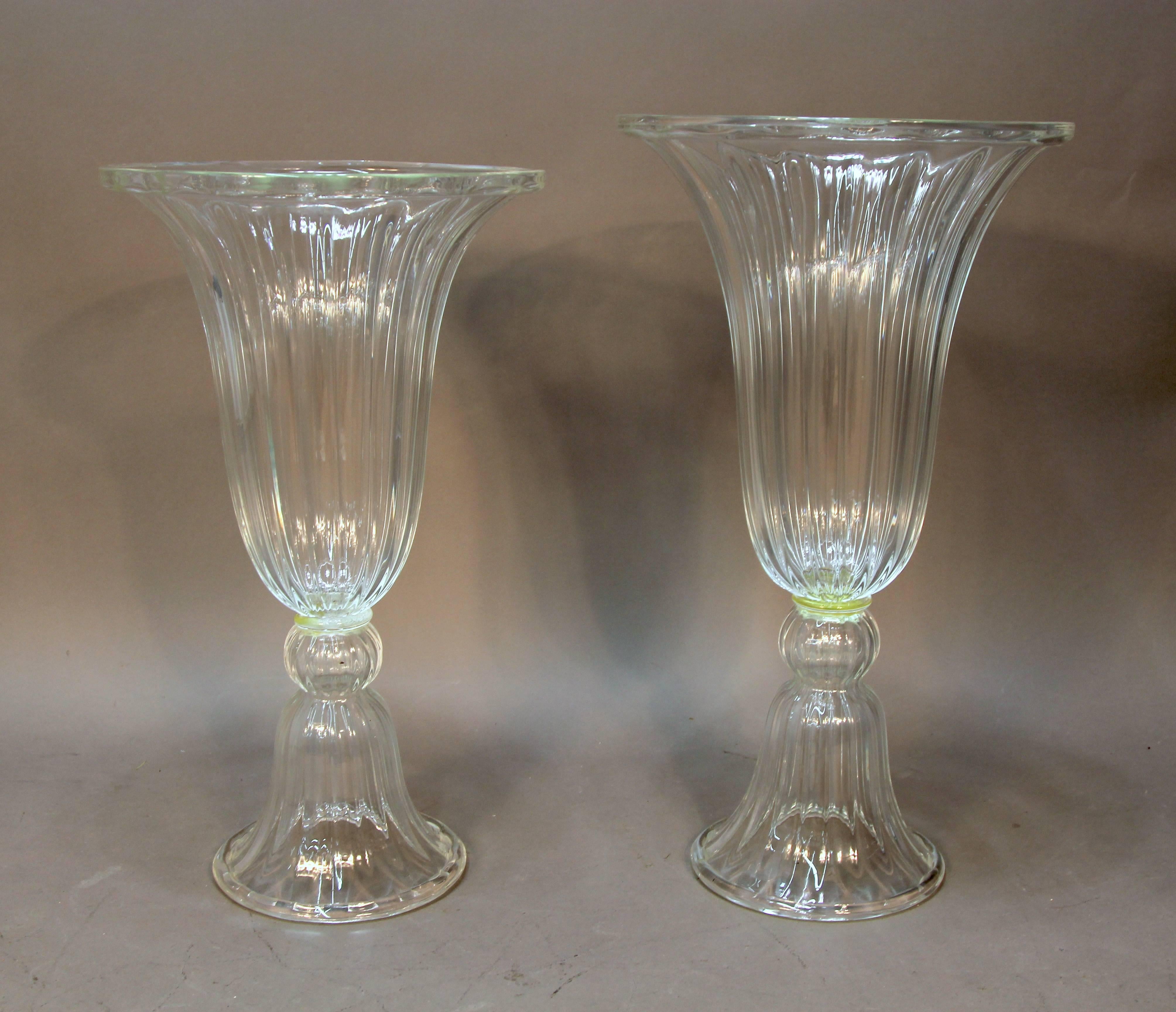 Substantial and deeply fluted glass vases with slight size variations typical of hand blow glass pairs. They are statement pieces, that would be equally at home on a modern credenza or in niches in a traditional environment. Out of a New York City