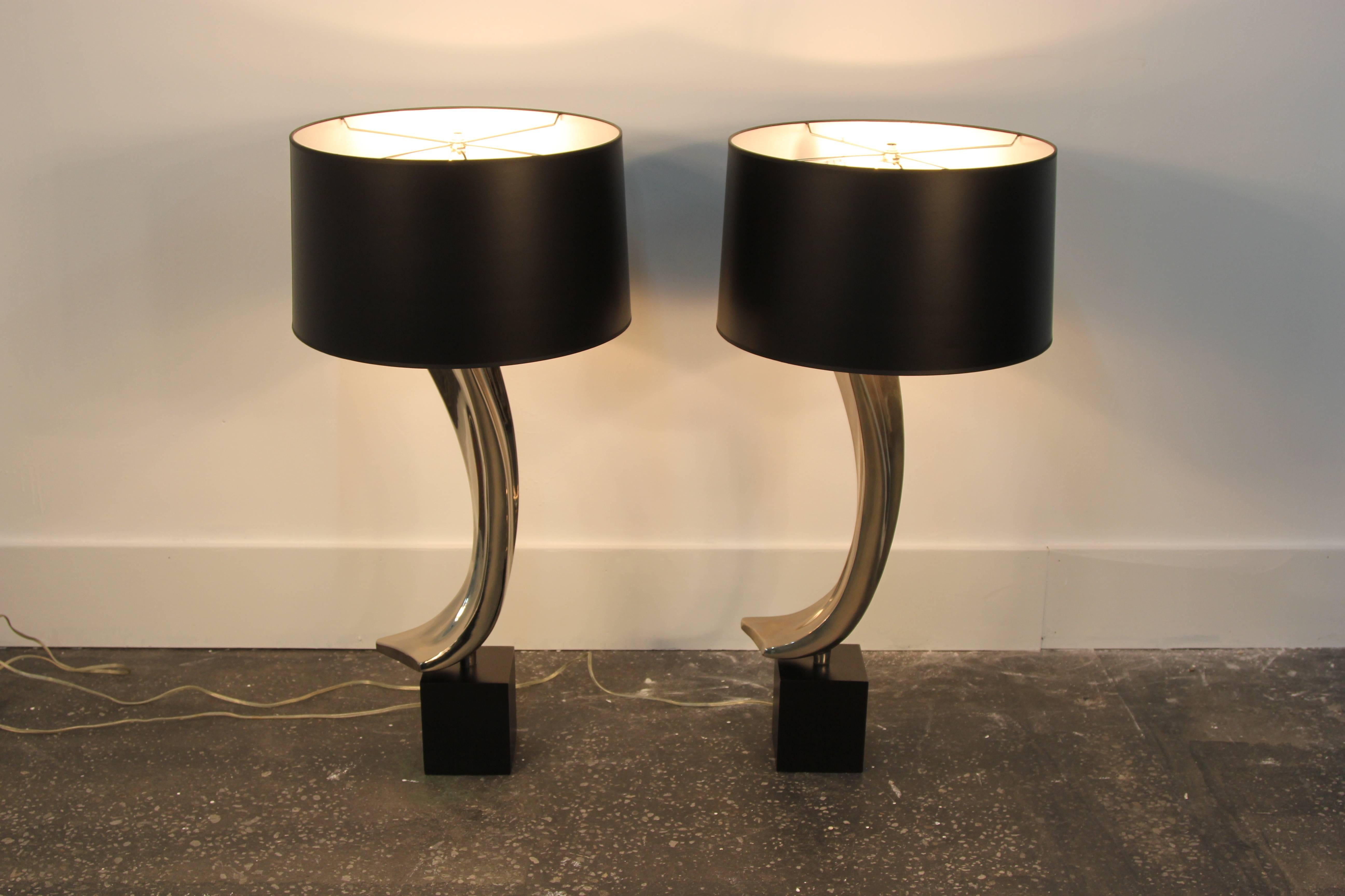 Amazing pair of polished chrome lamps manufactured by Laurel Lamp Co. Swooping chrome body, on square black box stands with new black paper shades with silver interiors.